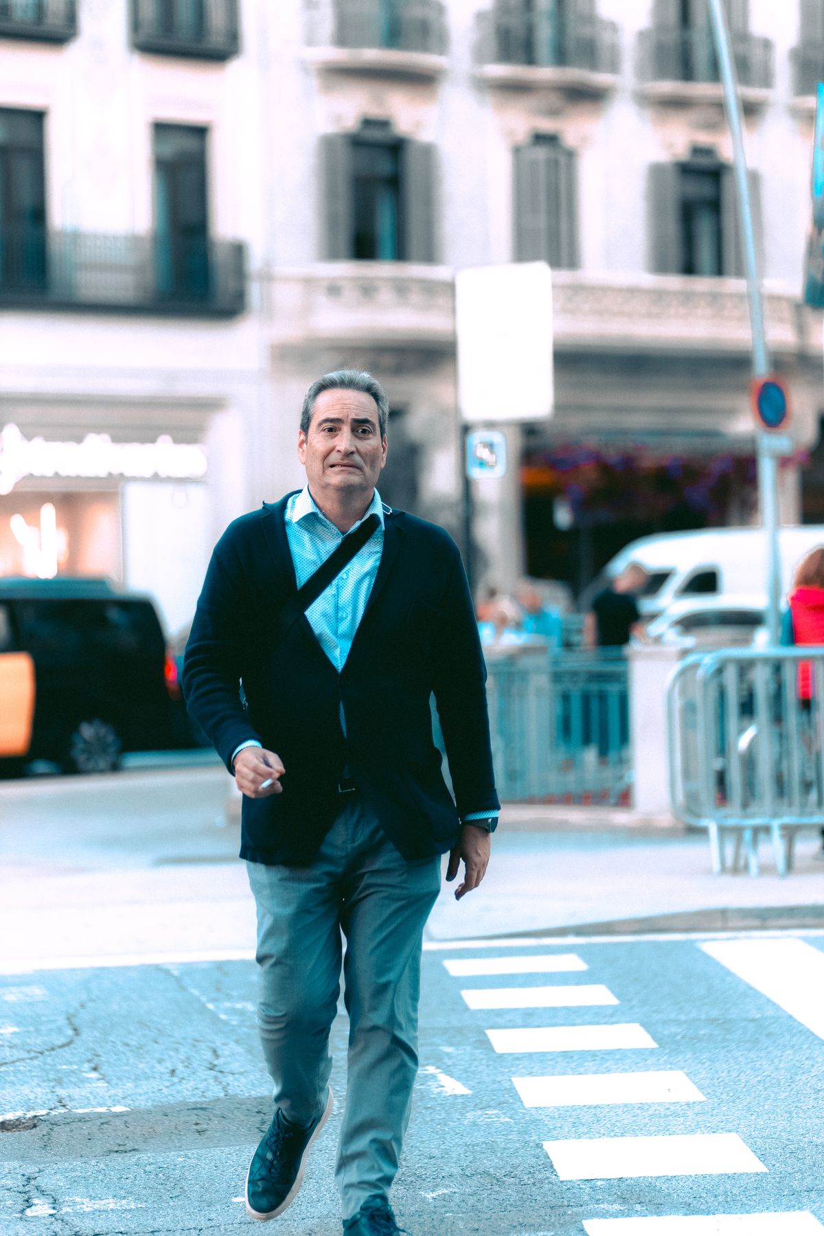 A dark casual jacket over a blue shirt with grey trousers.