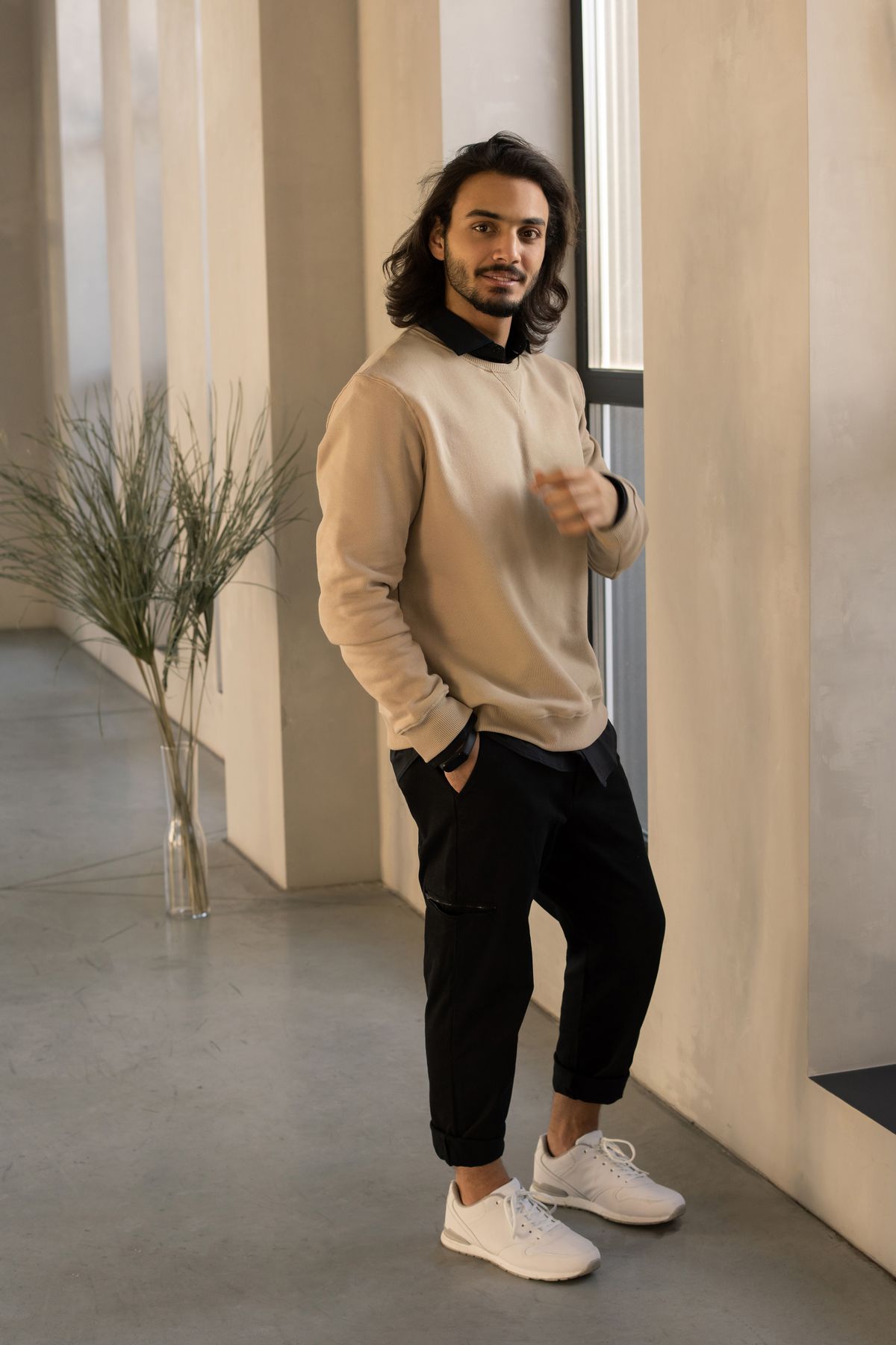 A beige jumper paired with black trousers and white trainers.