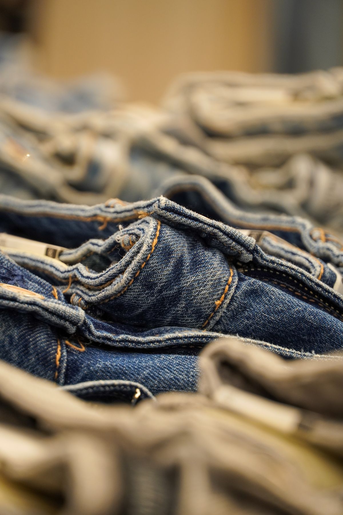 A close view of stacked denim waistbands, seams and woven texture.