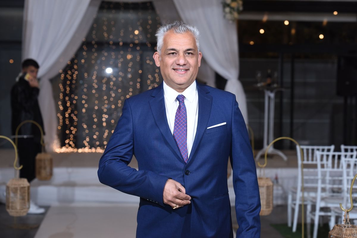 A man wearing a blue suit and purple tie at a celebration.