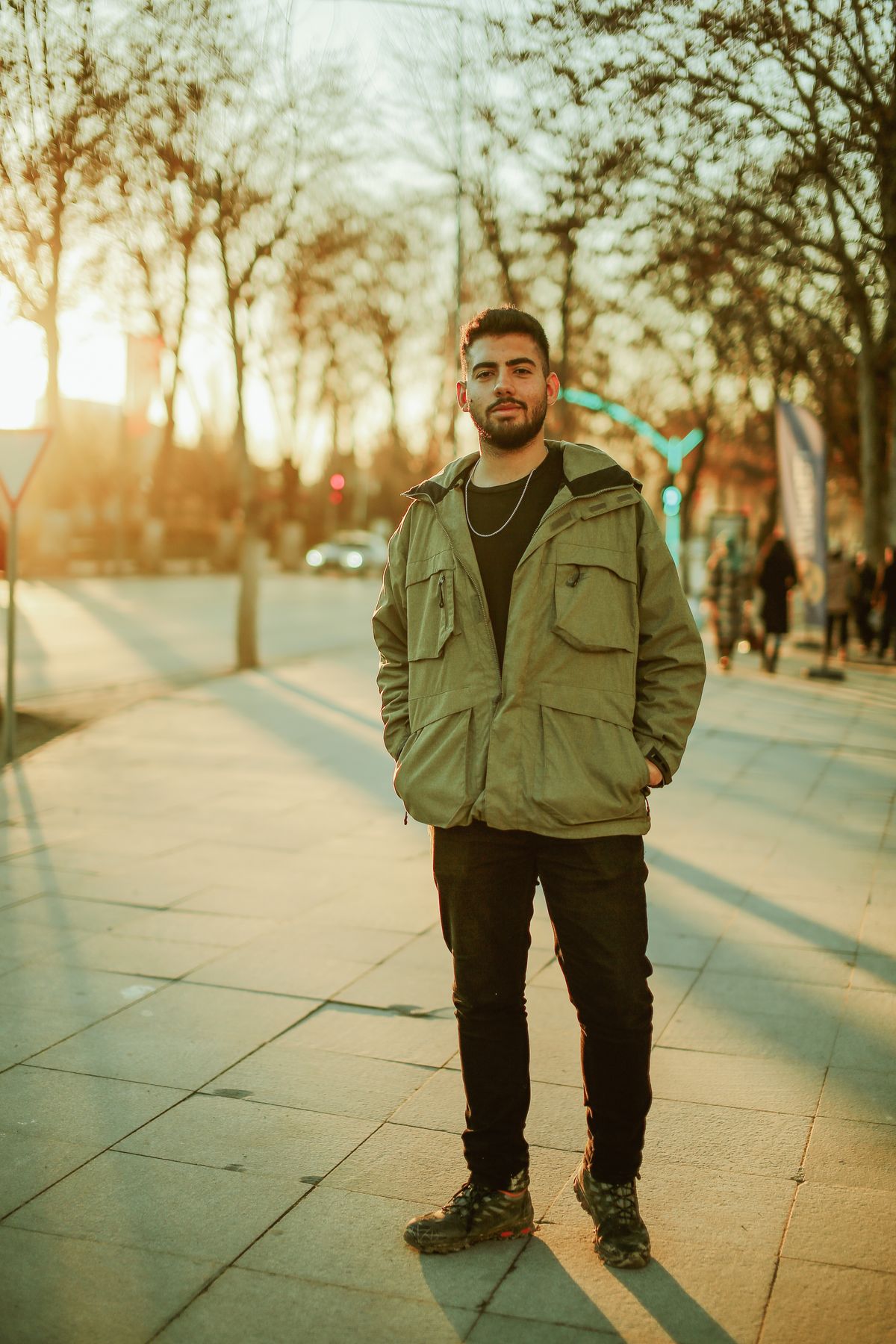 An olive field jacket with several flap pockets worn over a black top.