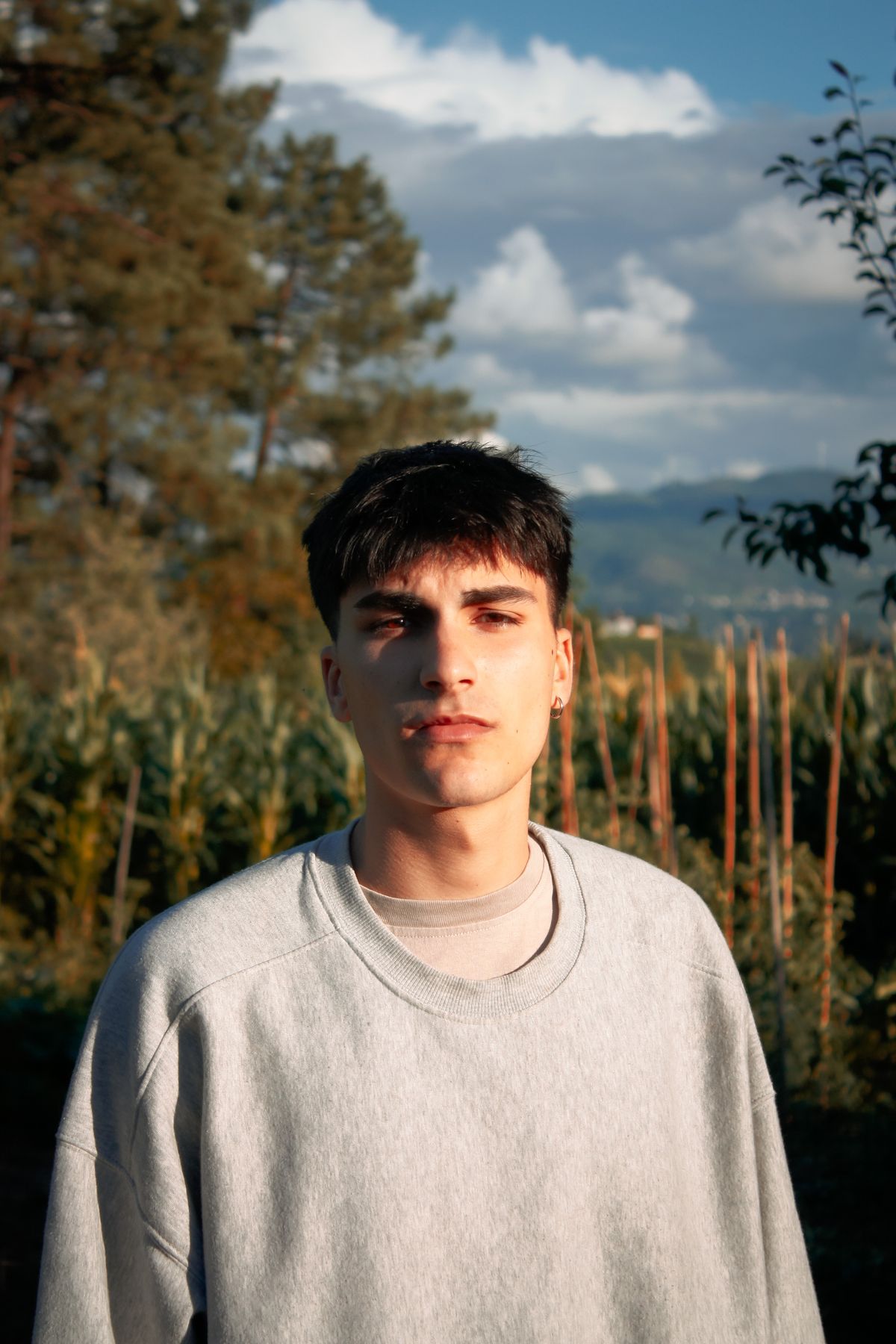 A man in a plain grey crew-neck sweatshirt outdoors.