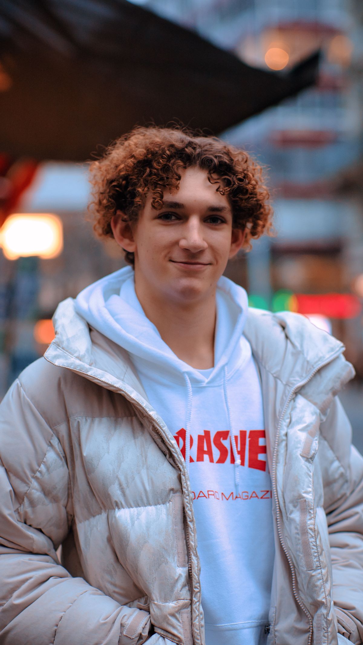 A white hoodie layered under a light padded winter coat.