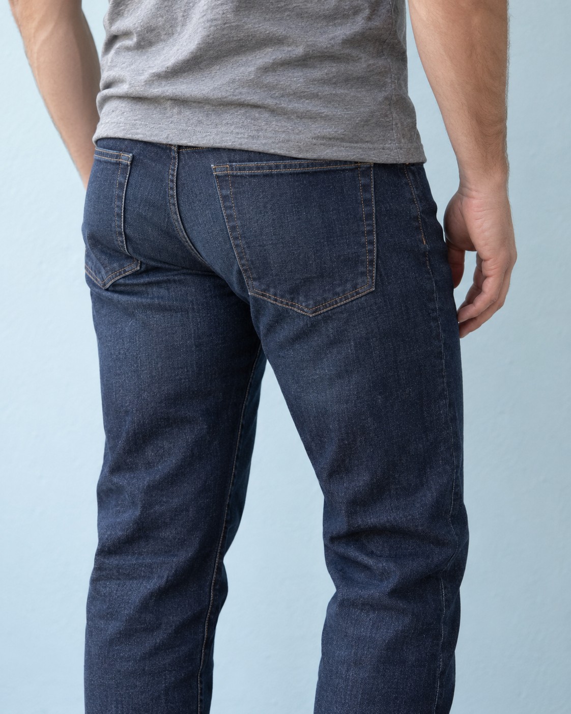 The seat and back pockets of straight dark-blue jeans.