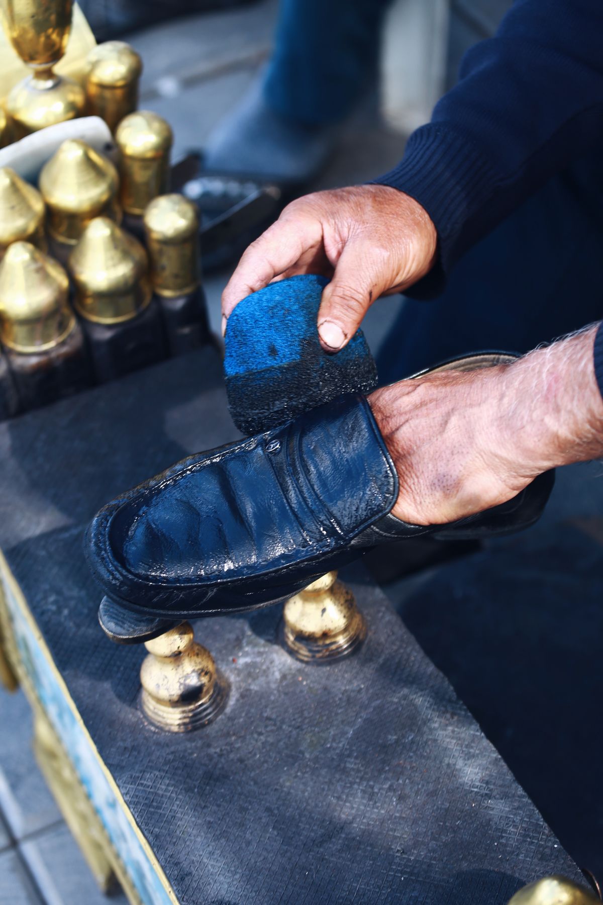 A person brushing a dark leather shoe.