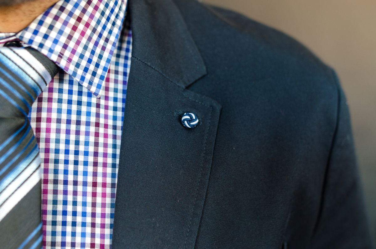 A checked shirt and striped tie beneath a plain dark jacket.