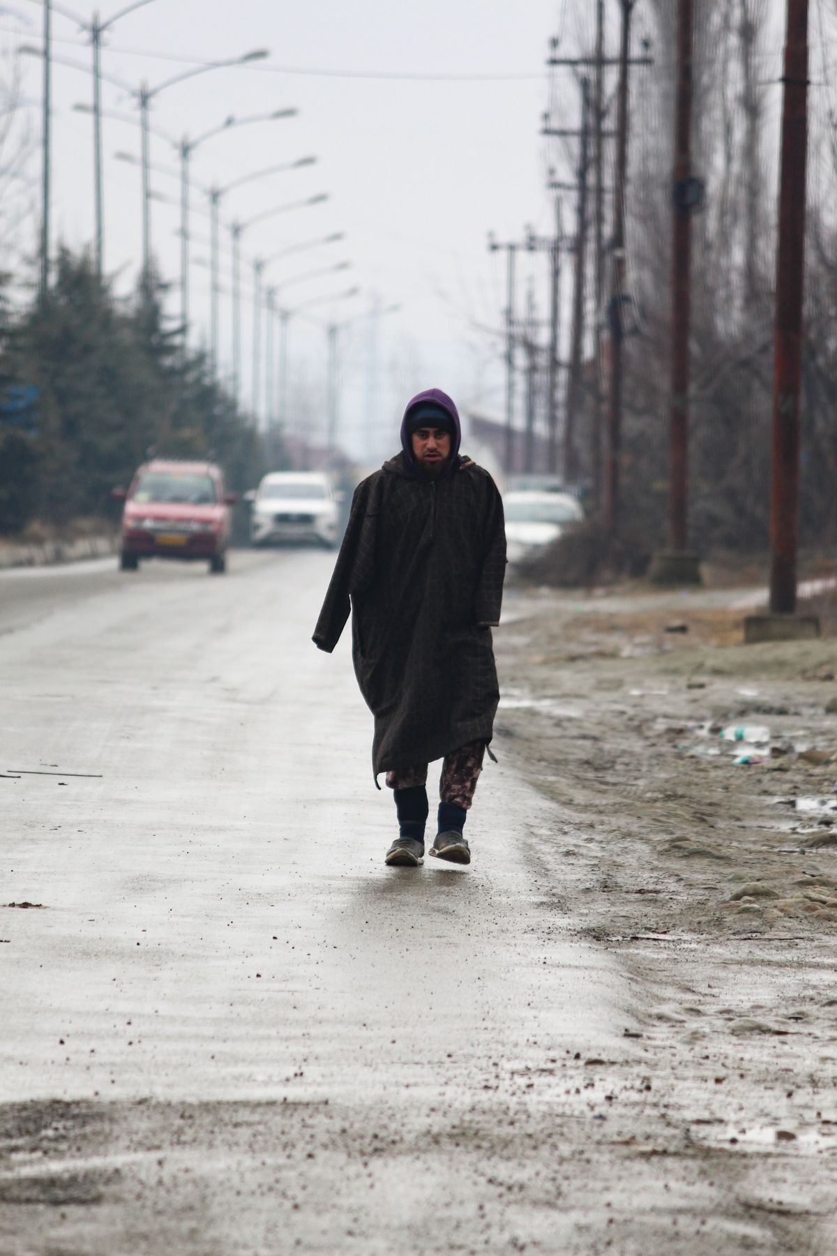A hooded raincoat worn on a wet street.