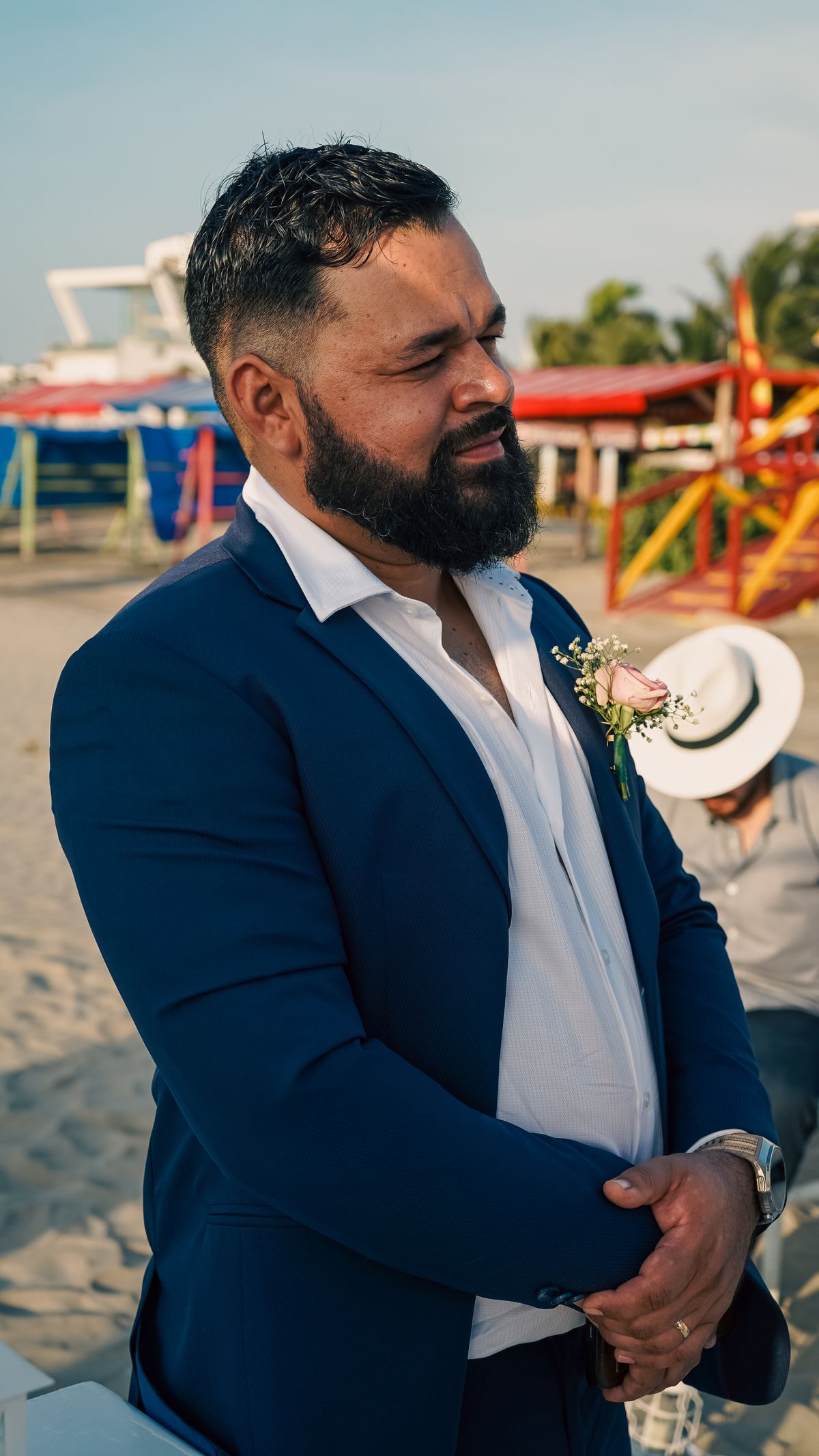 A navy suit and open-collar white shirt at a beachside wedding.