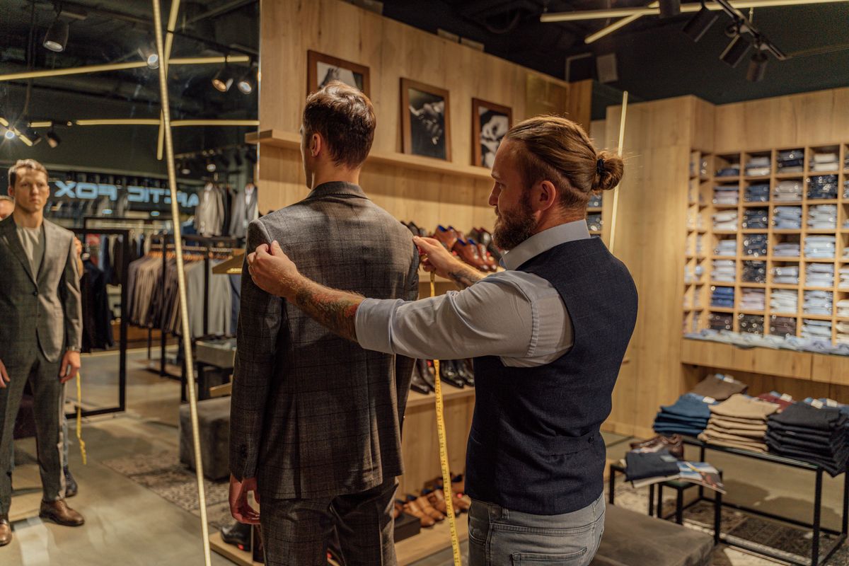 A tailor examining the back and shoulders of a checked jacket.