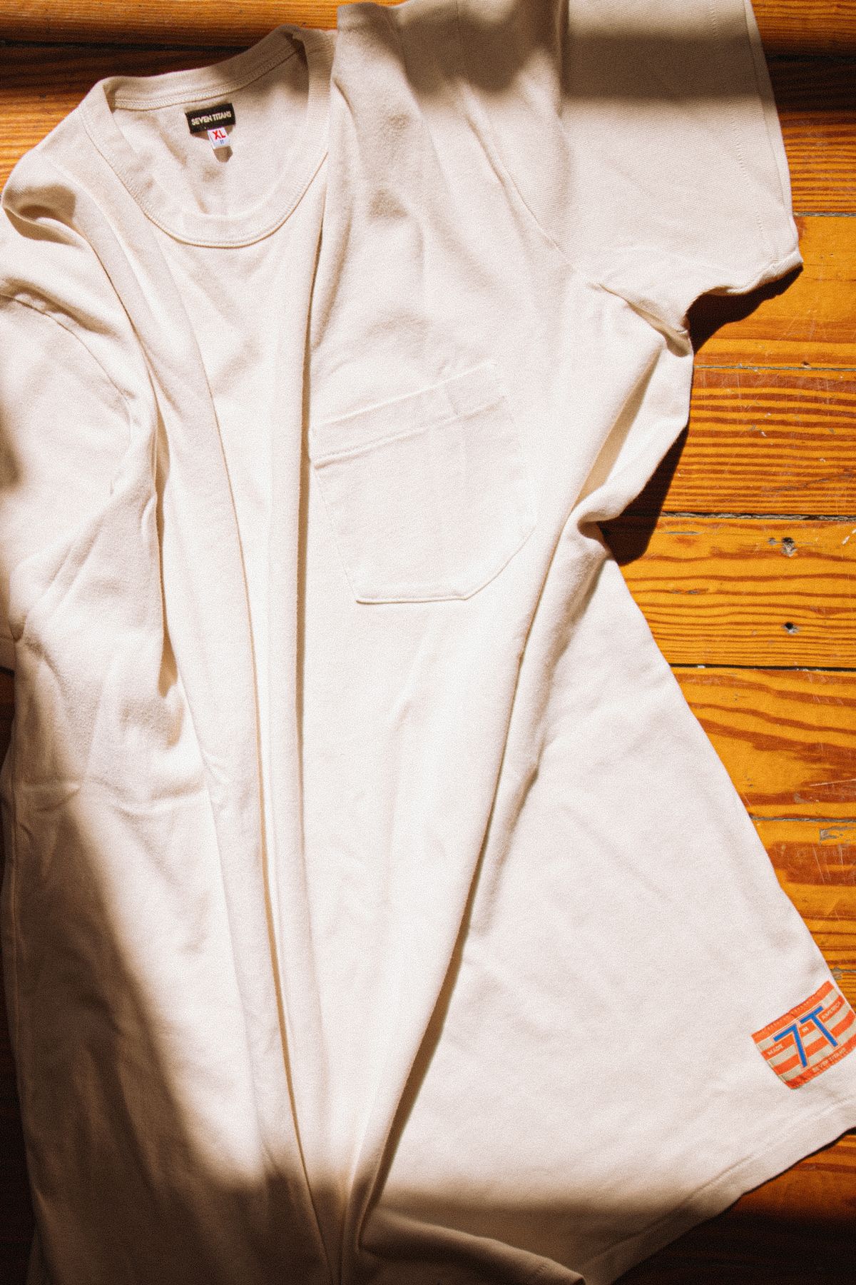 A close view of a white T-shirt laid on a wooden surface.