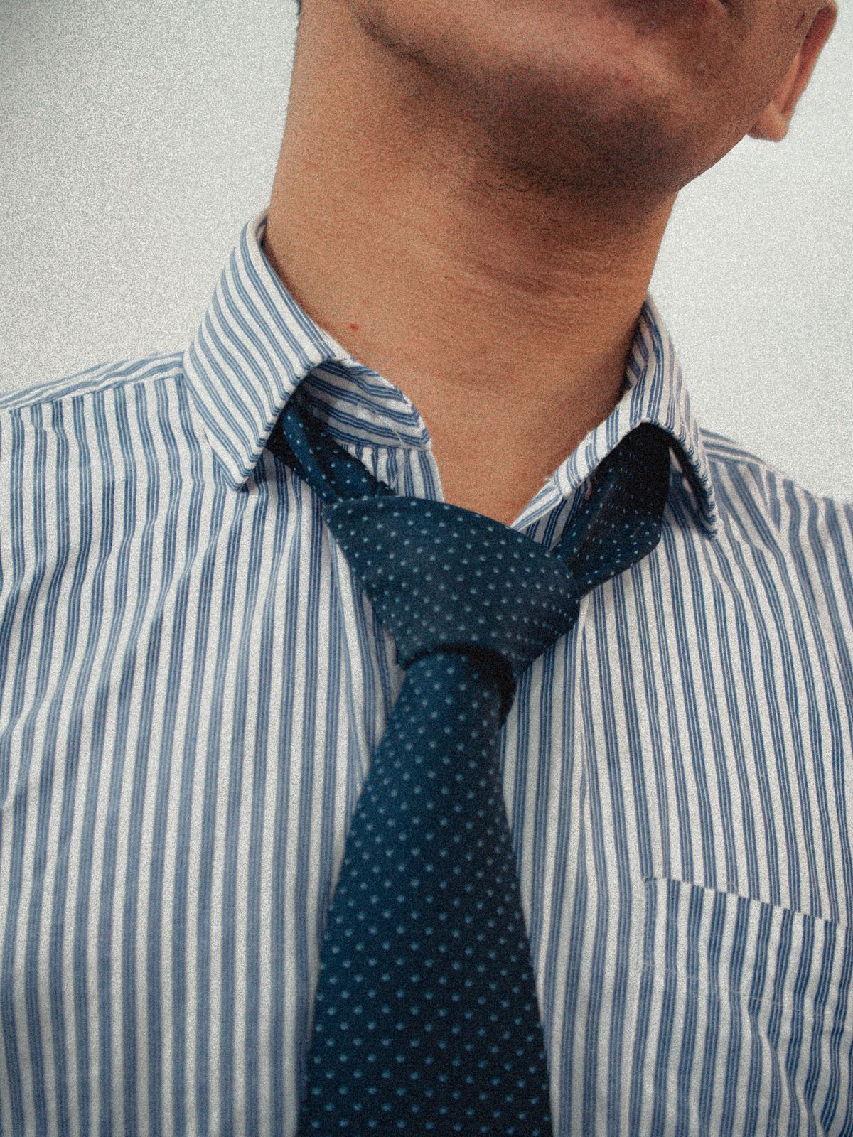 A blue patterned tie against a narrow-striped shirt.