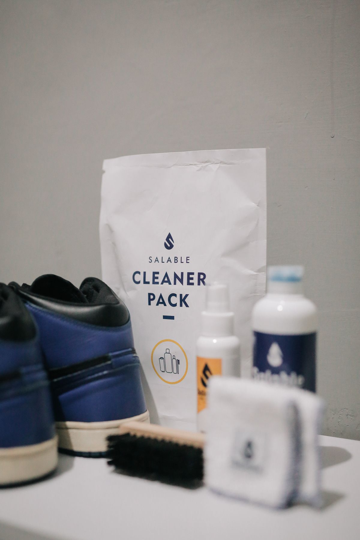 Trainers beside a shoe-cleaning brush and cleaning products.