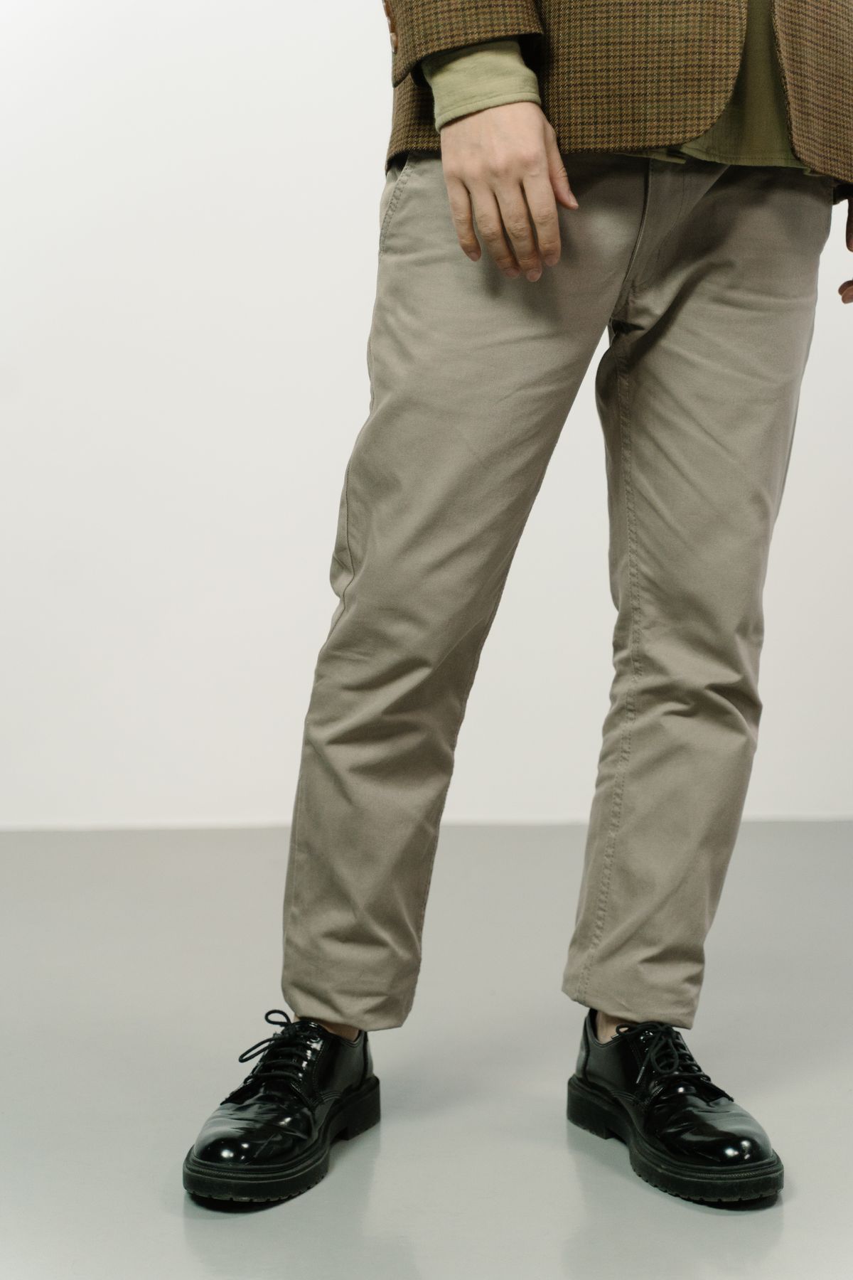 Straight trouser hems resting lightly above black leather shoes.