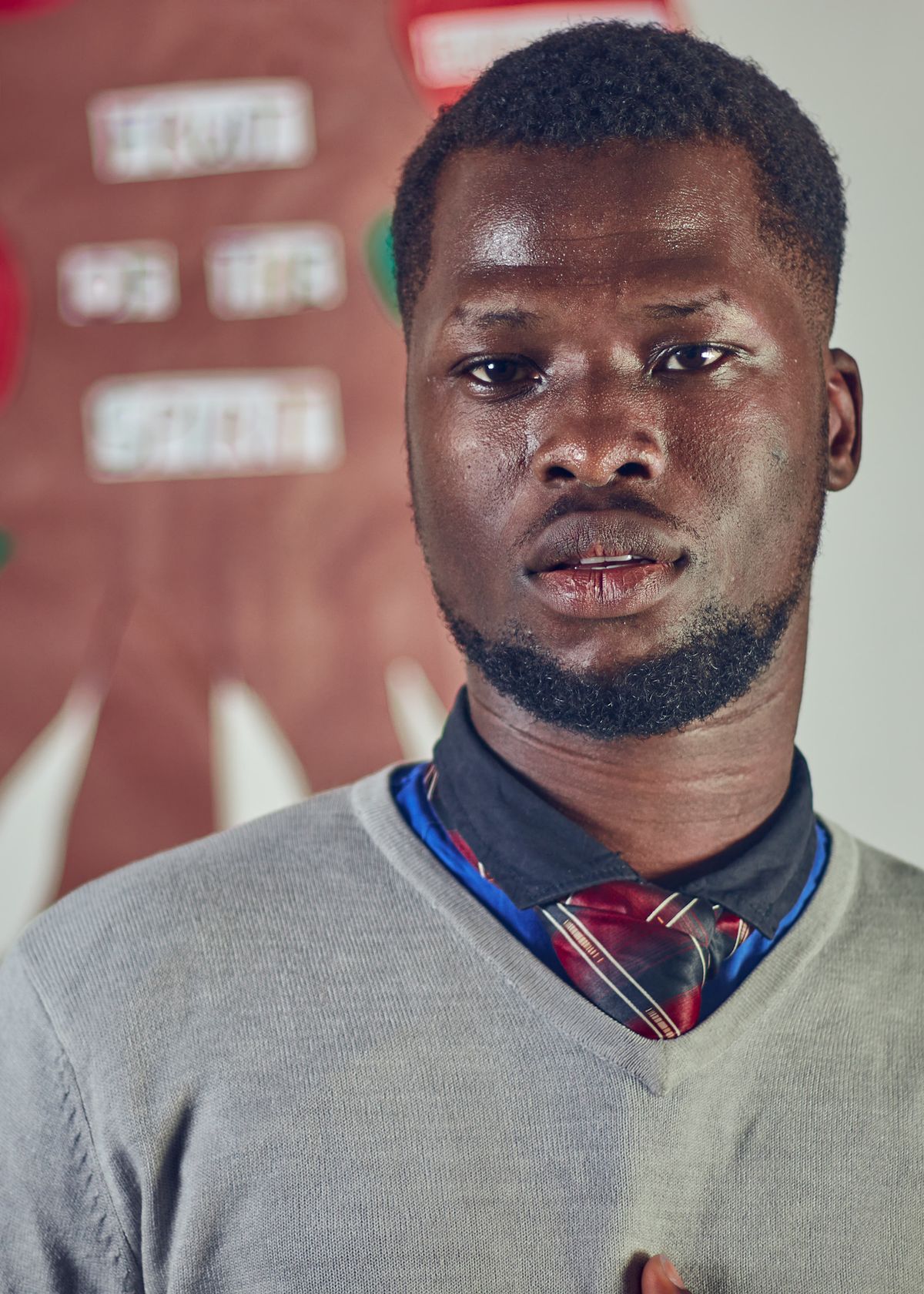 A grey V-neck jumper layered over a dark shirt and patterned tie.