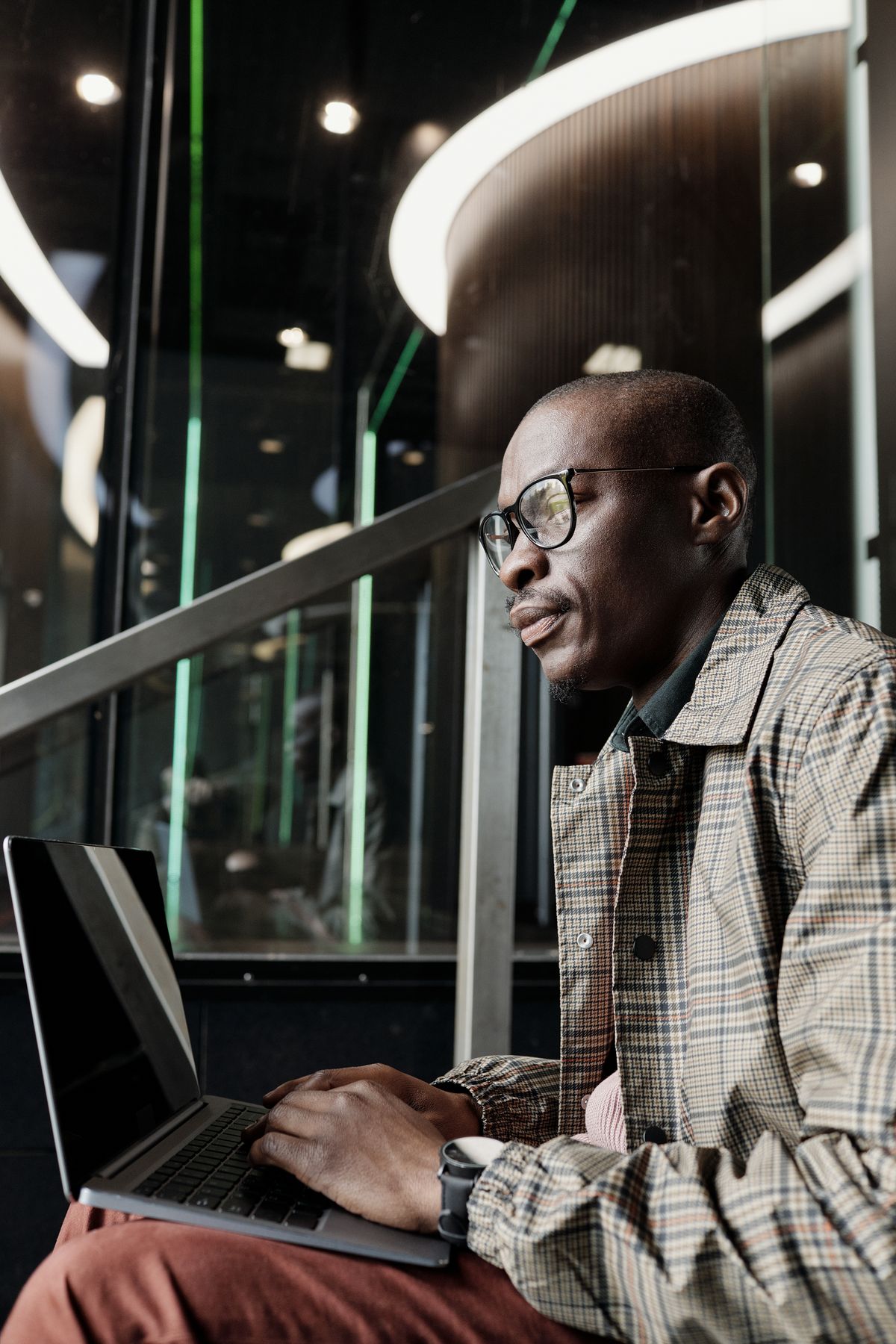 A man in a checked jacket working at a laptop.