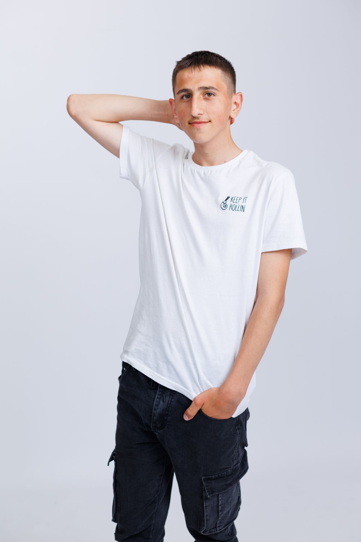 A man wearing a white crew-neck T-shirt with dark jeans.